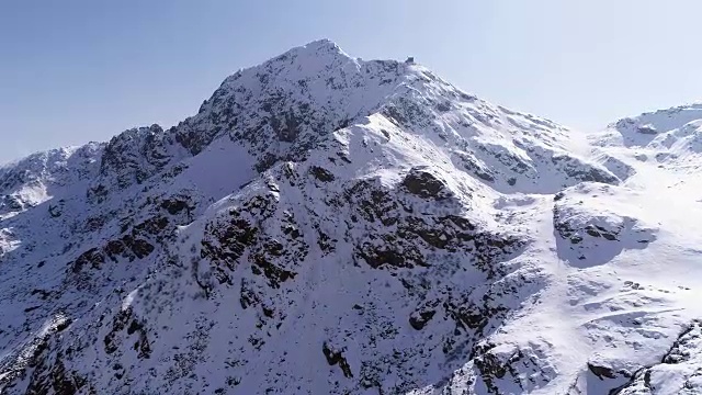 空中飞行向前移动，越过雪峰山脊建立。冬季户外雪高山野自然景观。4k无人机飞行建立镜头