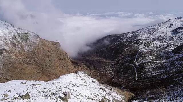 空中飞行向前移动的雪山山脊山谷与云彩和太阳建立。冬季户外雪高山野自然景观。4k无人机飞行建立镜头