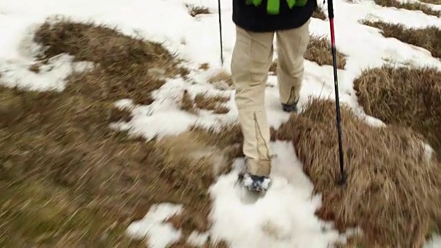 背包男徒步行走在雪道上。后面的腿细节。真正的背包客成人徒步旅行或徒步旅行在秋冬野外野外的山区自然，大雾天气恶劣