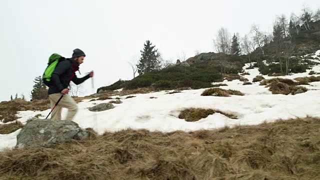 背包男徒步行走在雪道上。后一面。真正的背包客成人徒步旅行或徒步旅行在秋冬野外野外的山区自然，大雾天气恶劣。4 k的视频