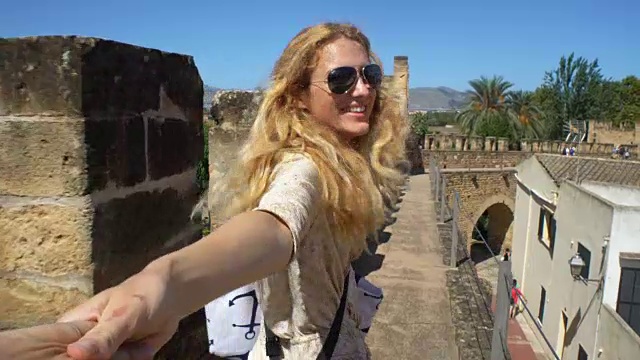 一个年轻女人带领一个男人在一个古老的欧洲小镇冒险