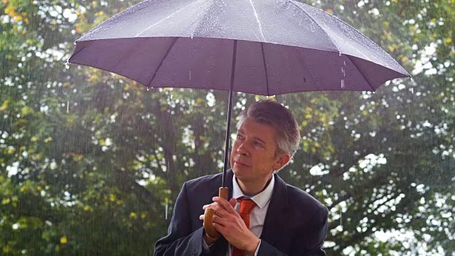 一个在雨伞下避雨的商人