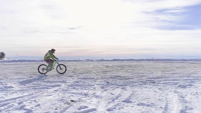 侧面的天线，在冬天骑着MTB电动车在雪道上骑车的人。冬天在户外雪地上骑自行车。4k无人机飞行视频