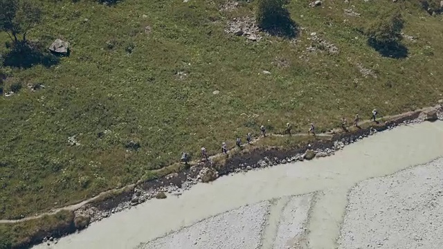 无人机观徒步旅行组沿山河行走。山之旅