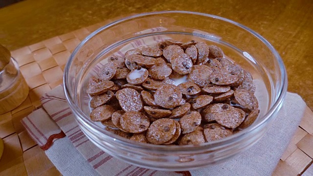 脆脆的巧克力片放在碗里，为早餐配上美味的牛奶。慢动作旋转跟踪镜头。