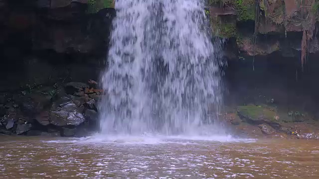 一个小瀑布的特写镜头与水溅在小溪流的底部
