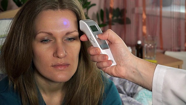 医生用数字体温计用手测量女病人的体温