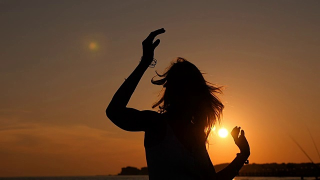 夏日自由:在海滩上日落时女子舞蹈的剪影