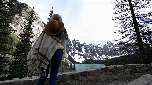 年轻女子在山湖边半空中跳着