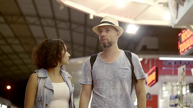 一对快乐的男女正在夜市上散步。一对夫妇去度假购物，他们选择纪念品和东西。集市