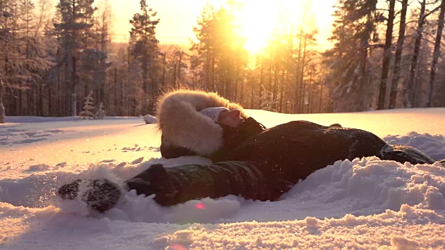 詳情圖-慢動(dòng)作頑皮的女孩在金色的夕陽(yáng)下在新鮮的雪中制造雪天使