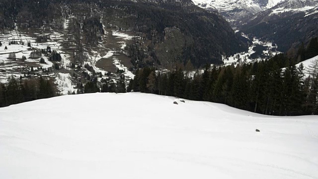 冬季无人机建立在滑雪者滑雪在雪山下的森林森林山谷。山区自然户外下雪。阿尔卑斯山滑雪登山活动。向前飞行。4k俯视图视频