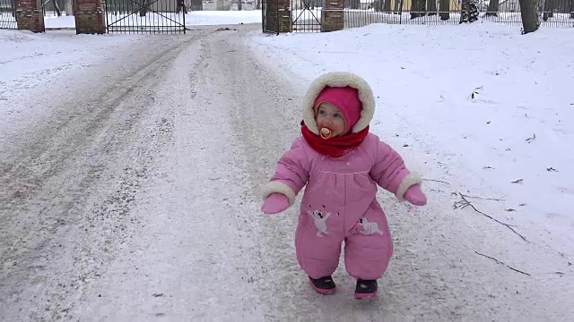 可爱的小女孩在冬天的雪地上快步走着。FullHD
