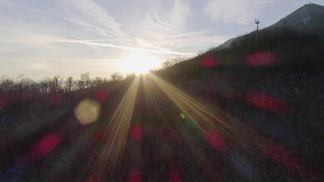 日落时分，无人机在白雪覆盖的森林上空飞行。冬天的雪在野外的山中自然。阳光的光。旅行探索阿尔卑斯山，4k俯视图视频