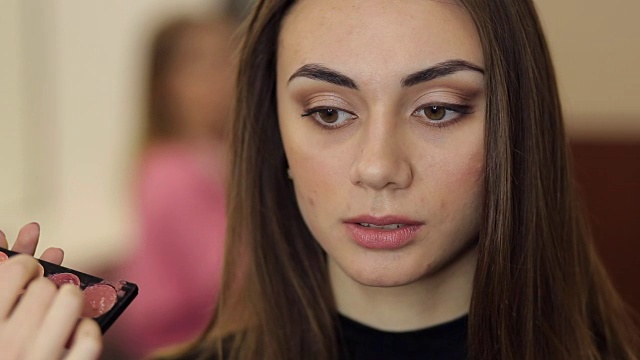 年轻女子在美容院给模特化妆。