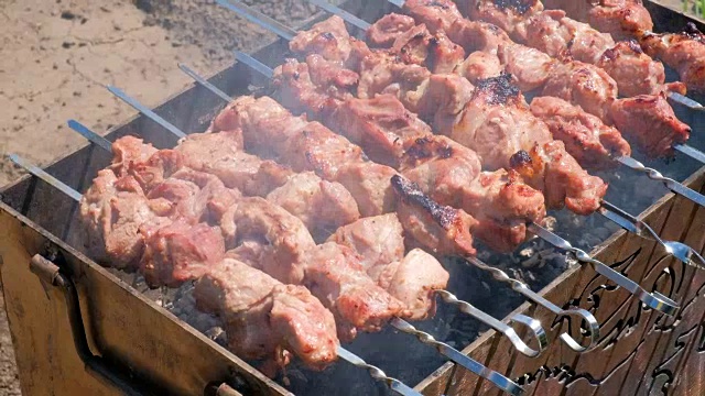 男人用烤肉串烤肉。男人的手在mangal上翻烤肉。烹饪野餐的食物。控制烤架上的食物准备。在炭火上烤烤肉。烤羊肉串