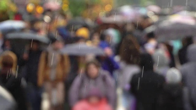 人们在繁忙的商业街撑着雨伞挡雨。真正的时间。黄色雨伞和黄色雨衣。人们在雨中带着雨伞上下班。模糊的散景。城市阴雨天的自然背景