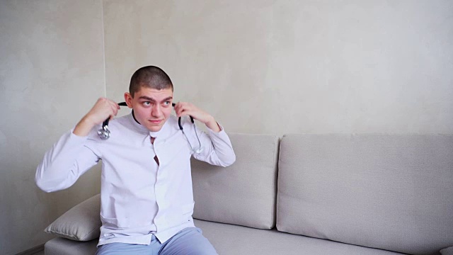 可爱的医生扣好制服，坐在以灰色墙壁为背景的办公室沙发上准备接待病人