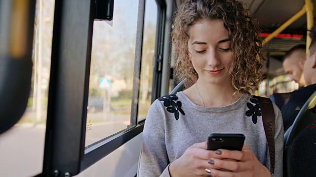 一位年轻女士在公交车上使用智能手机