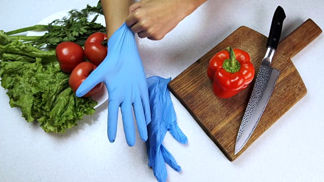 男人把手套戴在厨房里放蔬菜的桌子旁的胳膊上
