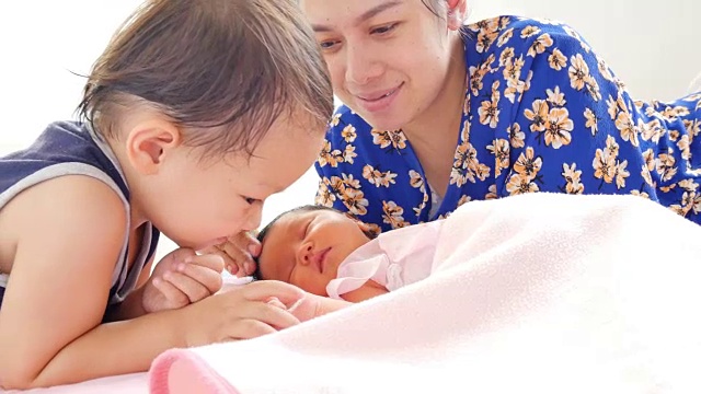 可爱的弟弟温柔地和妈妈和他的小女孩在摇篮里玩耍。舒适快乐的房子的概念。医疗保健舒适的童年