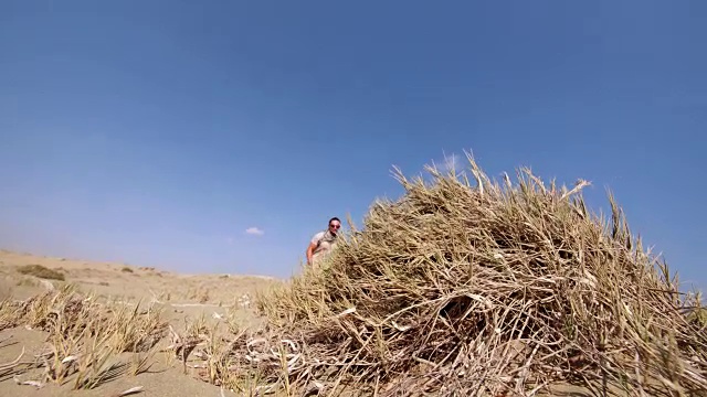 年轻的肌肉男在沙丘上做后空翻