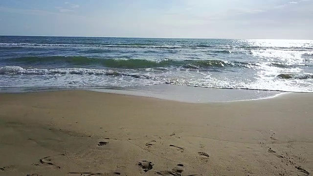 在阳光下闪闪发光的海浪到达海岸。航空摄影测量。慢动作