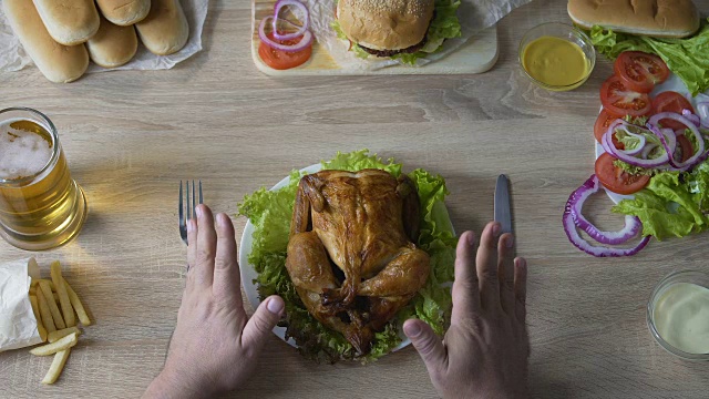 男人沉溺于不健康的饮食，把炸鸡放在桌子上，爱食物