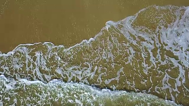 波浪在沙滩上留下花边图案。航空摄影测量。慢动作