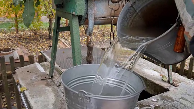 人们把铁链和水桶丢进乡下的井里打水。肮脏的水。