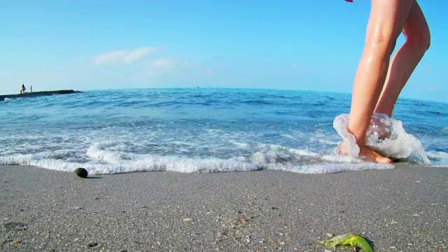 腿上只有年轻的少数民族女孩赤脚走在湿漉漉的沙滩旁边