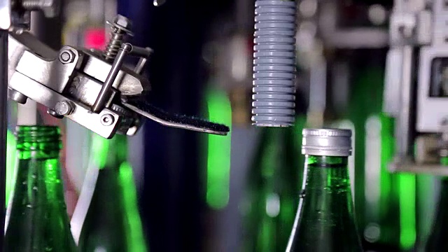 在水厂自动盖上瓶盖。绿色玻璃瓶自动输送线。近距离