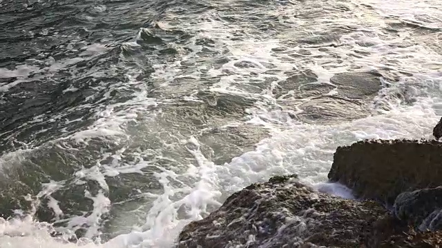 海浪拍打着多石的海岸形成浪花和泡沫。慢动作