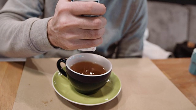 一个不知名的超重男子在茶中加入了甜味剂，这是糖尿病的后果。缓慢的运动。特写镜头
