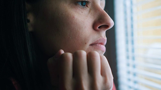 悲伤的女人透过窗户看