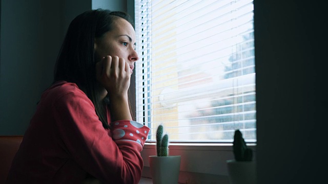 悲伤的女人透过窗户看