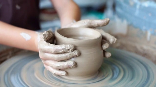 制作陶罐陶工陶土作坊陶土在装置上。大师。双手在陶土轮上工作，塑造一个陶土壶