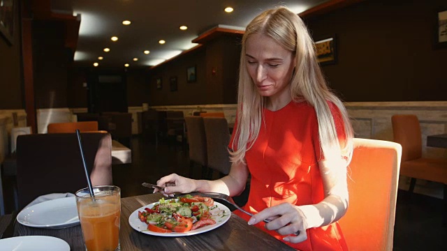 穿红衣服的女人在咖啡厅吃新鲜的沙拉