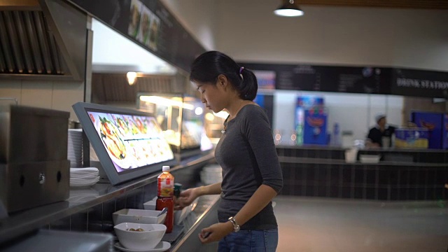 年轻的亚洲女士在美食广场往菜里加香料