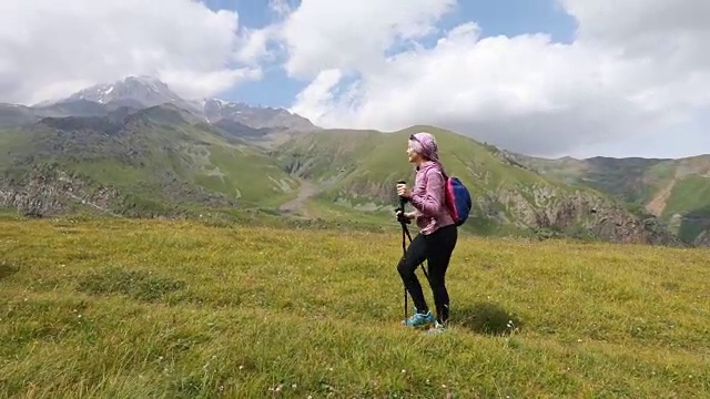 徒步旅行者沿着狭窄的峰顶行走。达到顶端。践行健康积极生活方式的年轻女性