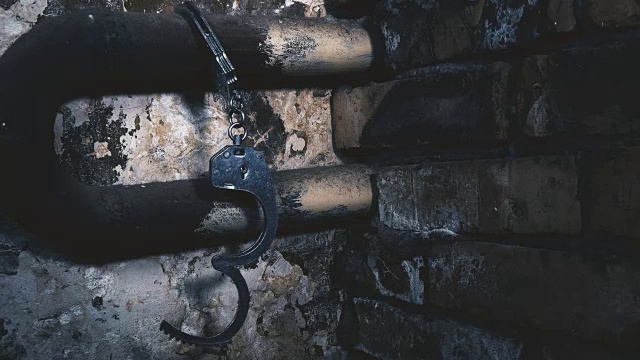 详情图-手铐被锁在一栋旧建筑的管子上