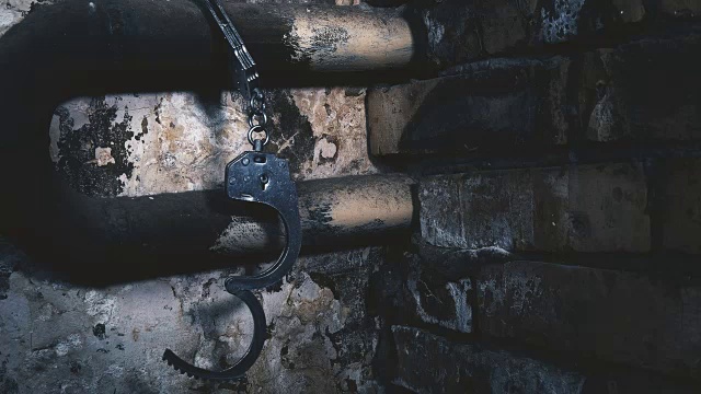 详情图-手铐被锁在一栋旧建筑的管子上