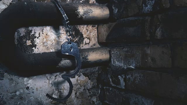 详情图-手铐被锁在一栋旧建筑的管子上
