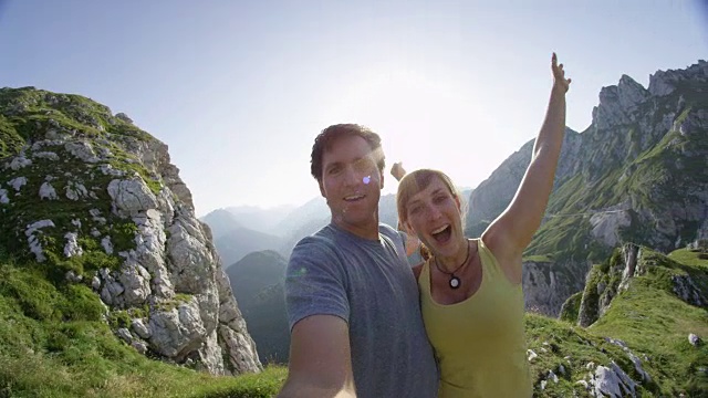 疯狂的年轻徒步旅行者在爬完山丘后举起手臂表示胜利