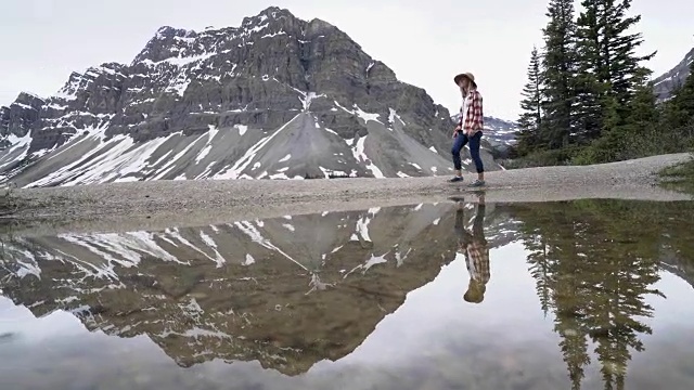 女人在湖边散步，湖光山色秀美