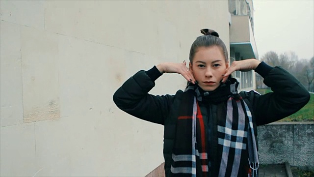 性感的女人在白色的砖墙上化妆跳舞