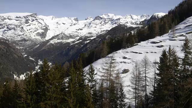 冬季无人机建立雪山下的森林森林山谷。雪山在户外自然。向前飞行。旅行探索阿尔卑斯山，4k俯视图视频