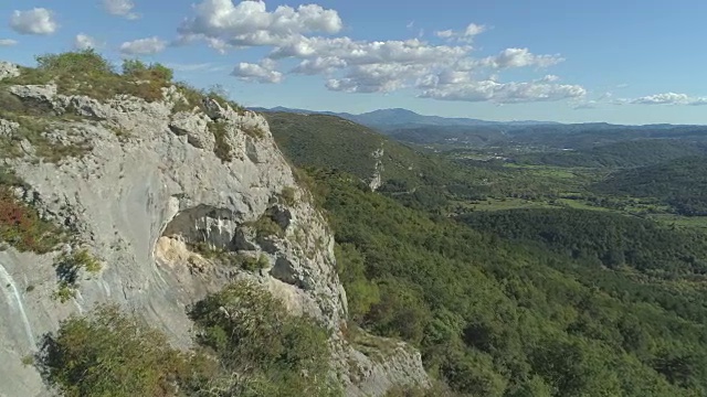 空中:飞过岩石峭壁，飞向长满树林的草地和山丘。