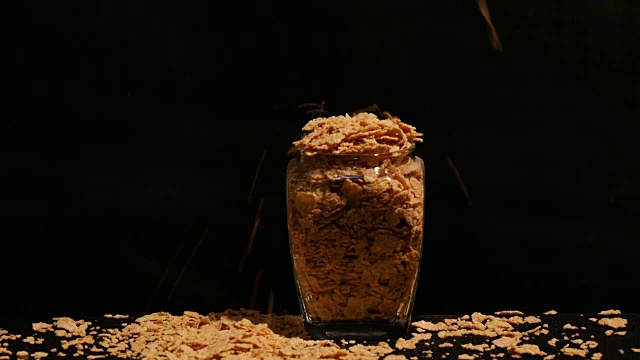 将大量的玉米片倒入黑色的玻璃杯中