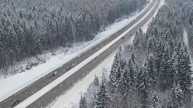 在冬天的森林里开着车在下雪。空中全景。消失点的角度来看